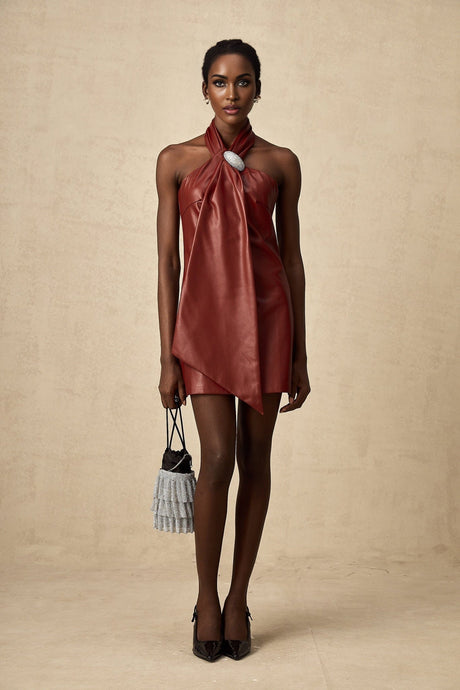 A woman wearing a vibrant red mini dress made of sheepskin with a halter neckline the dress has a form fitting silhouette and ends above the knees