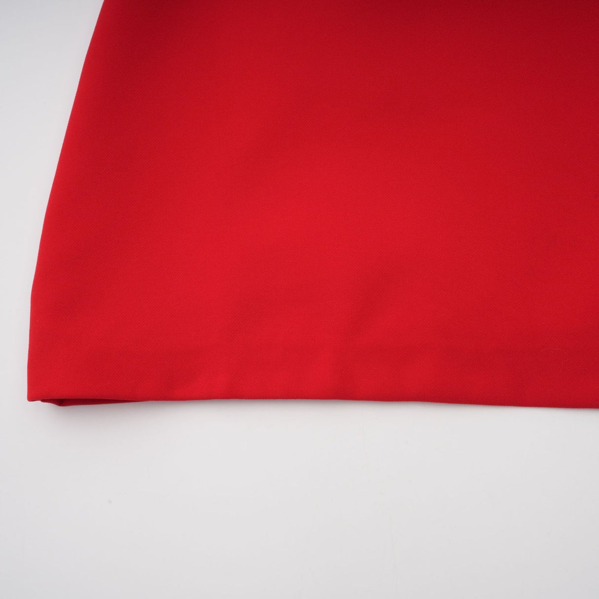 A woman wearing a vibrant red mini dress with cap sleeves standing against a plain background