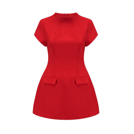A woman wearing a vibrant red mini dress with cap sleeves standing against a plain background