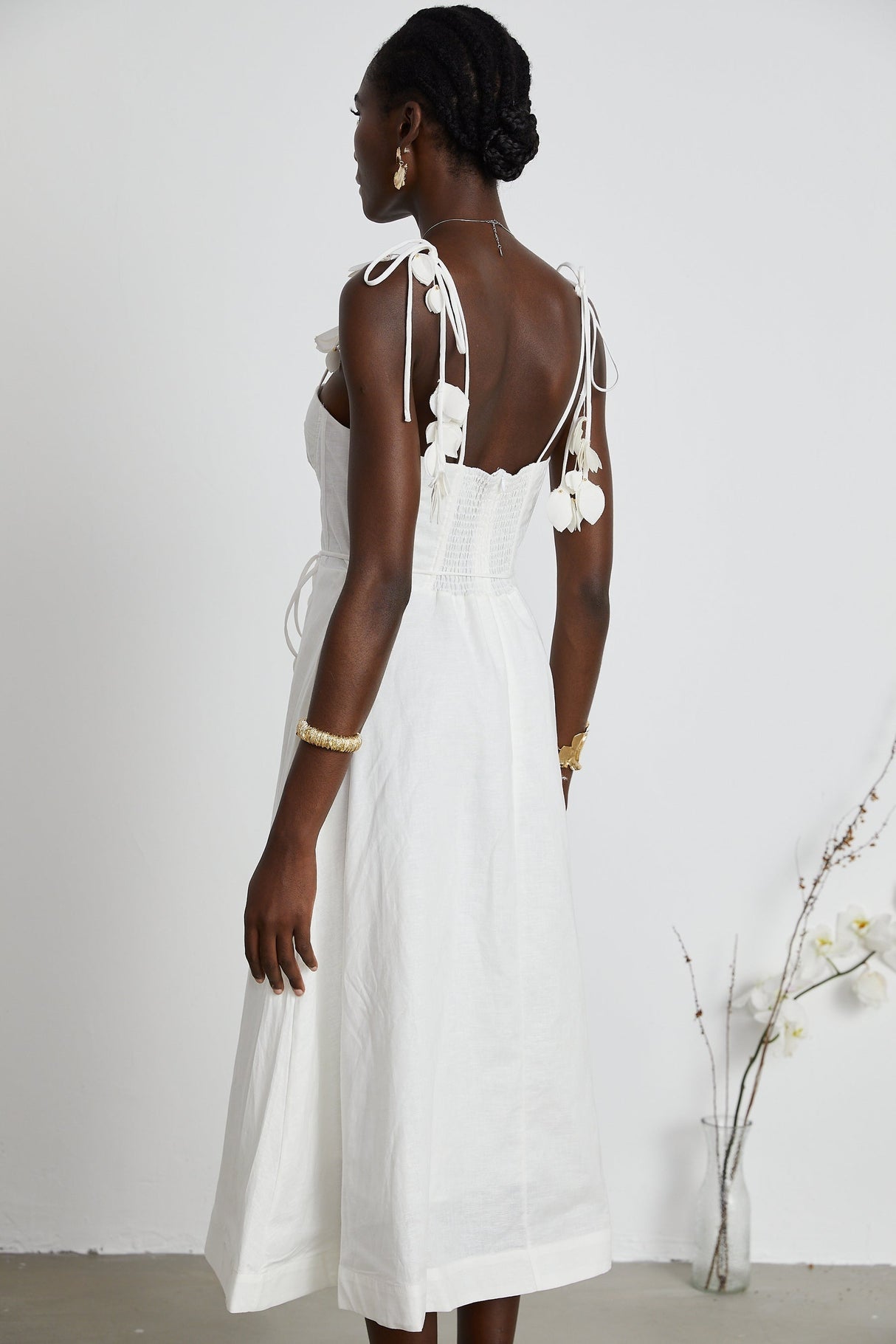 A woman wearing a white corset midi dress with a fitted bodice and flared skirt standing against a plain background