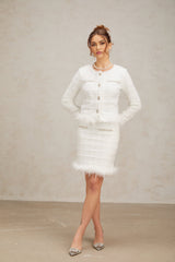 A woman wearing a white feather waffle knit cardigan and matching skirt set posing against a neutral background