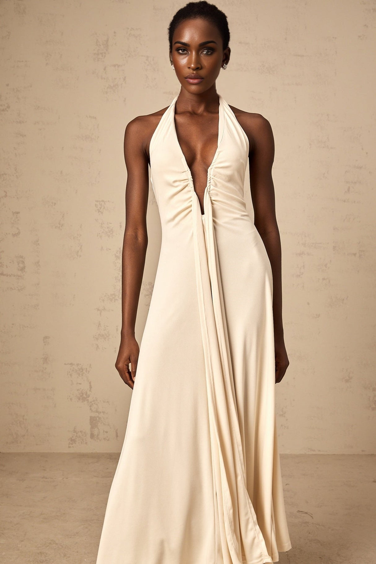 A woman wearing a white floorlength dress with a deep V neckline and draped fabric details