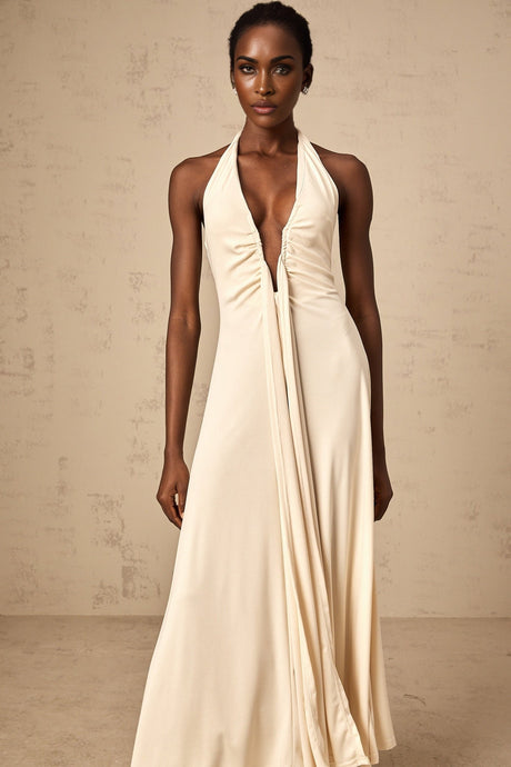 A woman wearing a white floorlength dress with a deep V neckline and draped fabric details