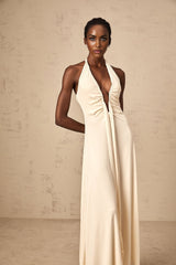 A woman wearing a white floorlength maxi dress with a deep V neckline and draped fabric detail