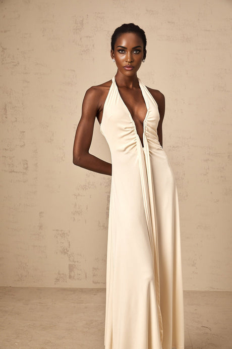 A woman wearing a white floorlength maxi dress with a deep V neckline and draped fabric detail