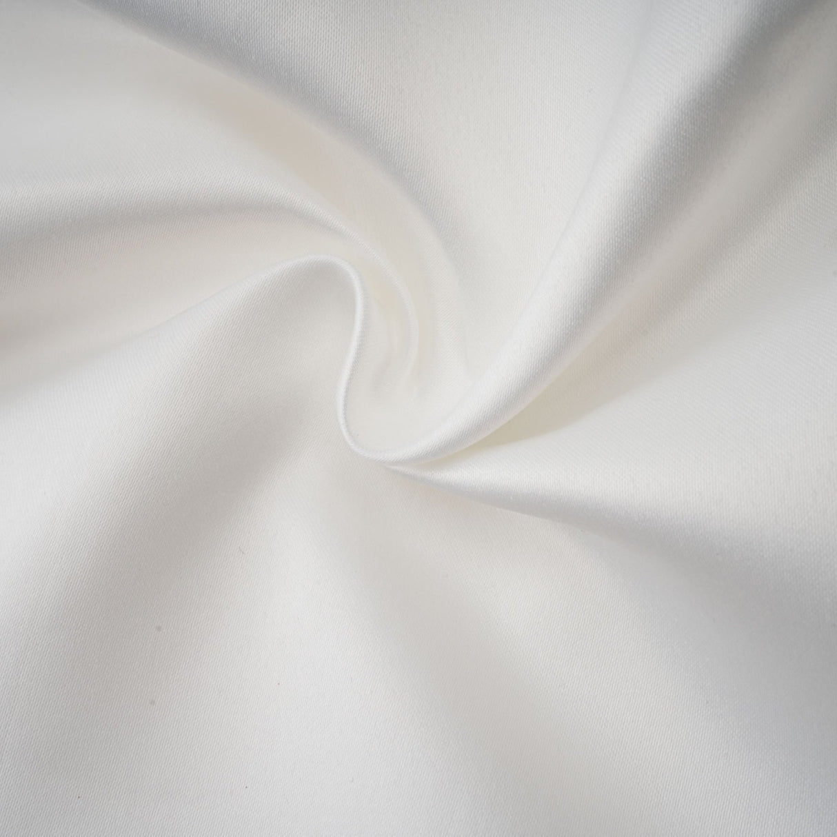 A woman wearing a white halterneck mini dress with ruffles standing against a plain background