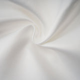 A woman wearing a white halterneck mini dress with ruffles standing against a plain background