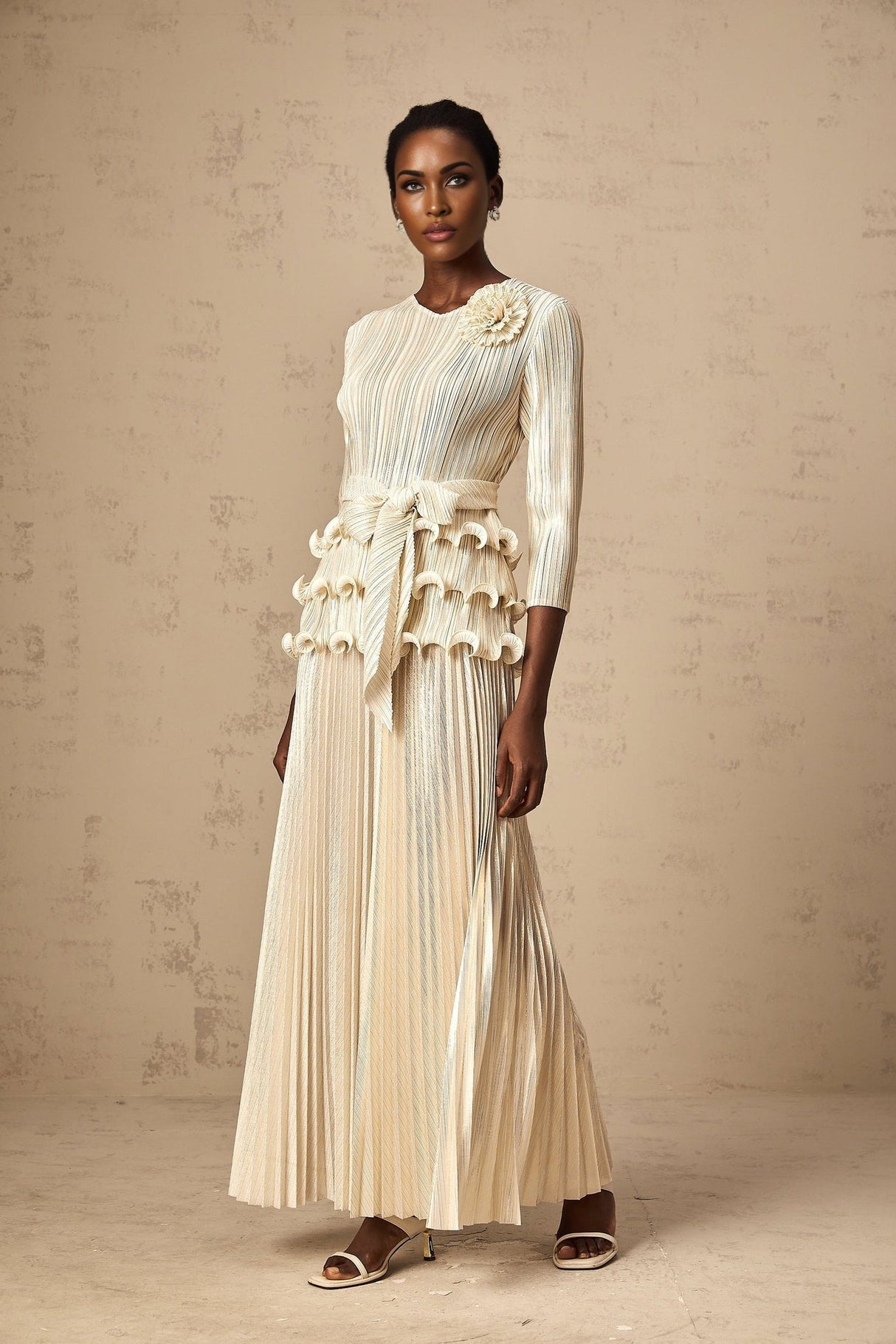 A woman wearing a white jumpsuit with floral appliques ruffles and pleated details