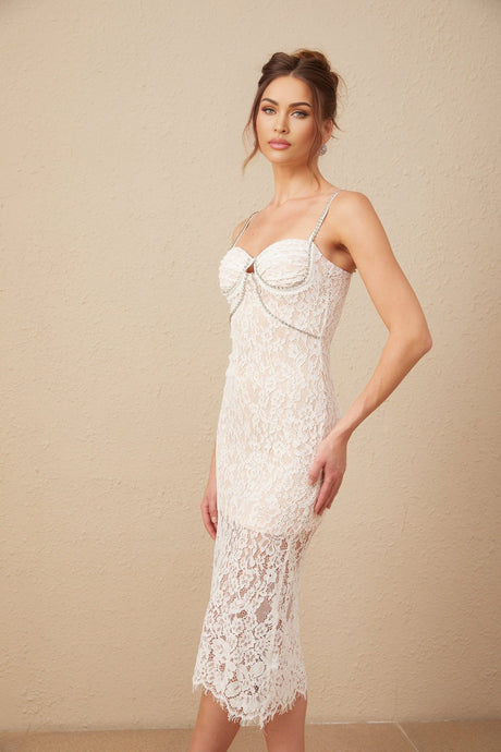 A woman wearing a white lace midi dress with a crystal embellished bustier top and delicate floral lace pattern throughout the bodice and skirt