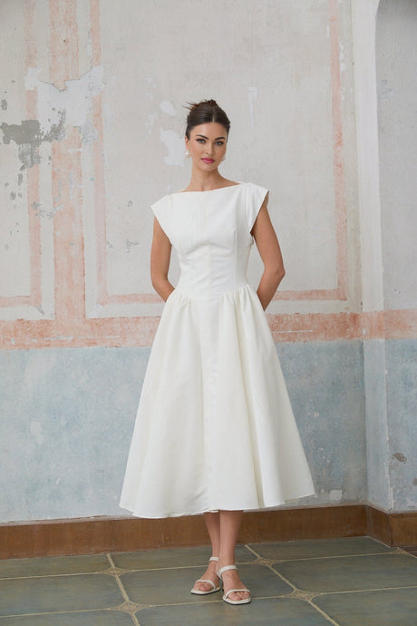 A woman wearing a white midi dress with cap sleeves and an open back design