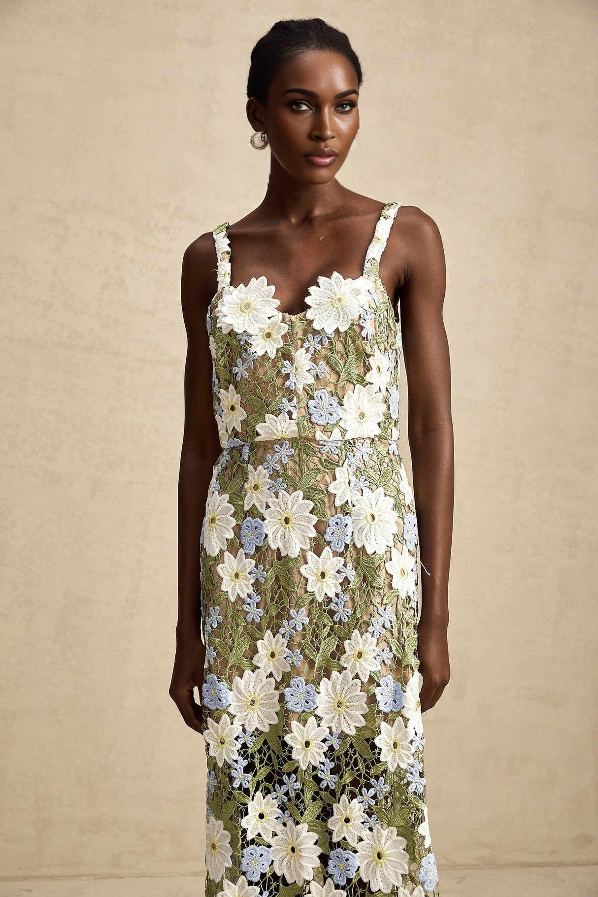 A woman wearing a white midi dress with floral embroidery and cutout details standing in a relaxed pose