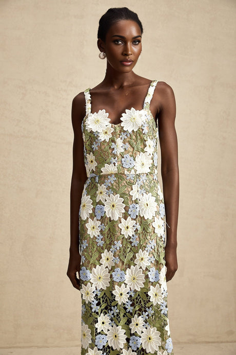 A woman wearing a white midi dress with floral embroidery and cutout details standing in a relaxed pose