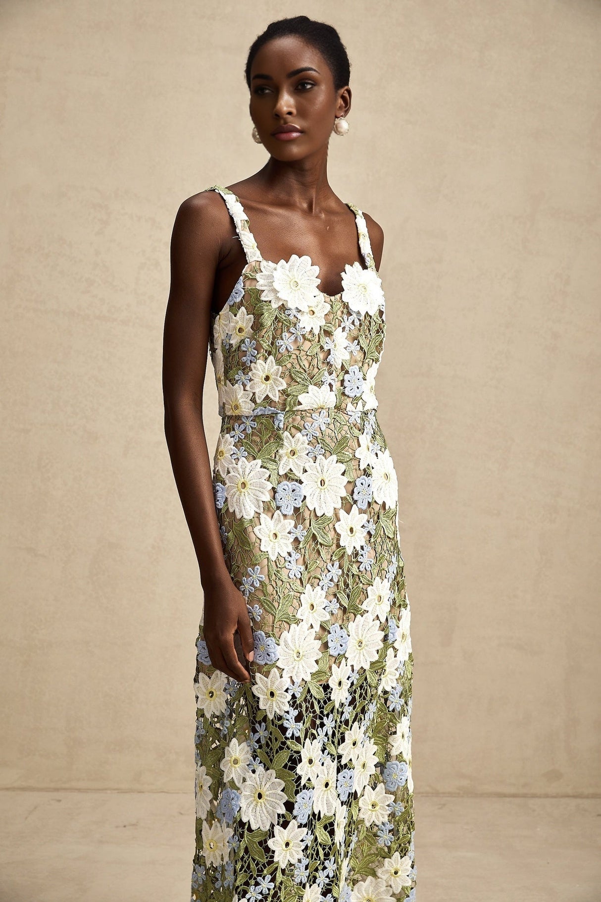 A woman wearing a white midi dress with floral embroidery and hollow carved details standing in a relaxed pose