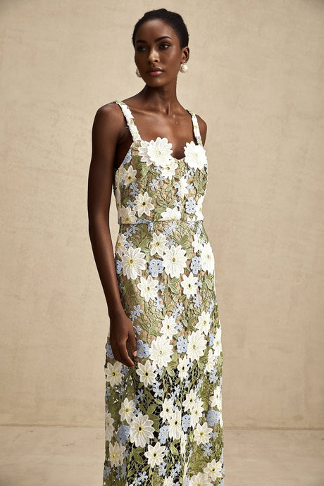 A woman wearing a white midi dress with floral embroidery and hollow carved details standing in a relaxed pose