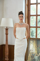 A woman wearing a white twopiece outfit consisting of an embroidered top and matching skirt called the Margot set
