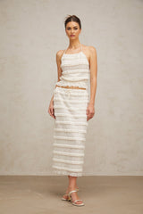 A woman wearing an off white floral lace matching set consisting of a ruffled top and skirt the top has short sleeves and the skirt falls to mid thigh length