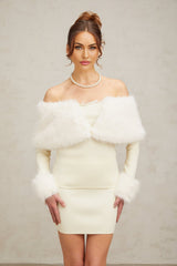A woman wearing an offwhite faux fur matching set consisting of a fine knit top and skirt standing against a plain background