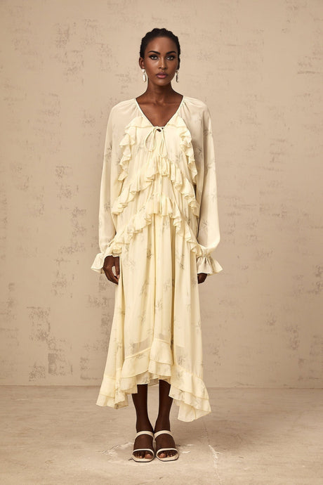 A yellow midi dress with a floral print pattern made of chiffon fabric featuring ruffle details and a flowing silhouette
