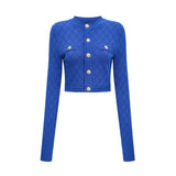 A young woman wearing a blue knitted two piece outfit consisting of a long sleeve top with button details and a matching skirt