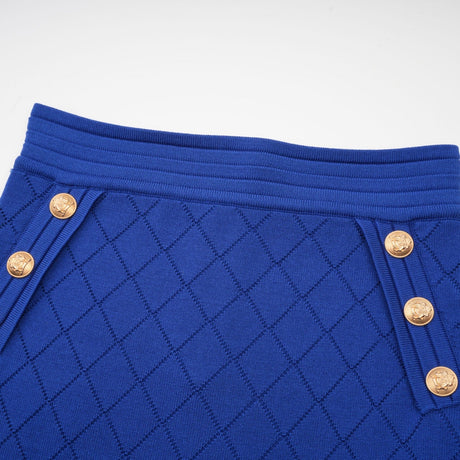 A young woman wearing a light blue knitted top and matching skirt set The top features button details and the outfit has a cozy yet stylish appearance