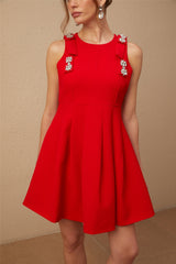 A young woman wearing a sleeveless red mini dress with a pleated skirt and a prominent bow detail at the front