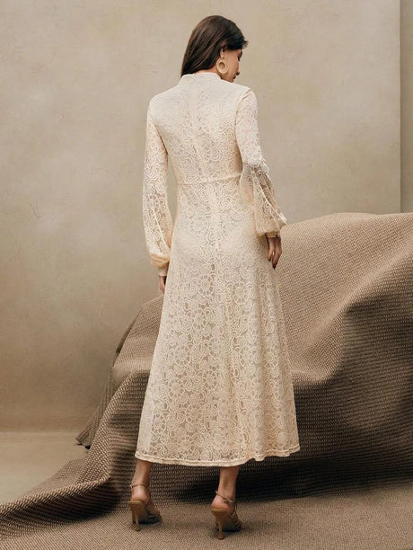 This elegant cream lace dress features a sophisticated high neck and flowing sleeves, offering a flattering fit that.