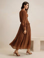 This elegant brown dress features a flowing maxi silhouette with delicate pleats and a fitted bodice, creating a.