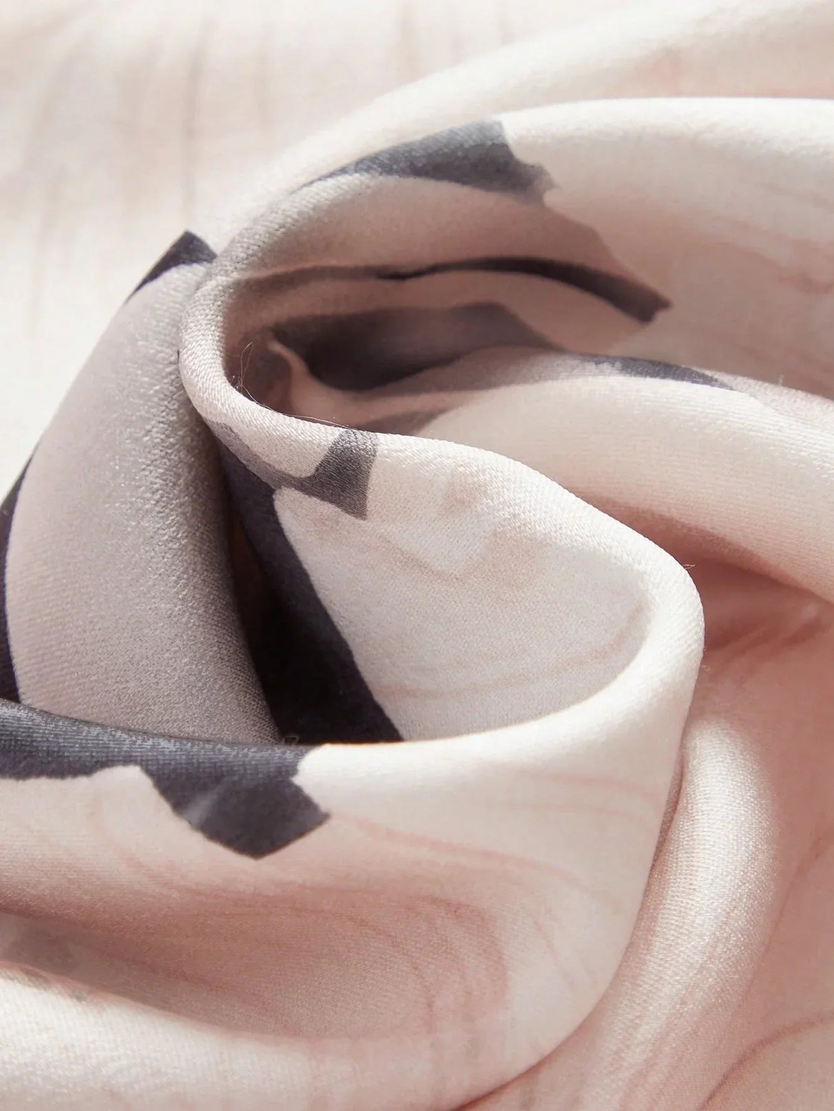 A soft and flowing dress featuring a delicate blush hue adorned with artistic black brushstroke patterns, crafted from.