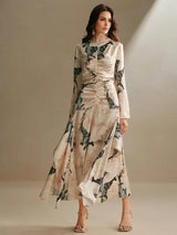 Featuring a soft blush color adorned with large, vibrant floral prints, this elegant long-sleeve dress showcases a.