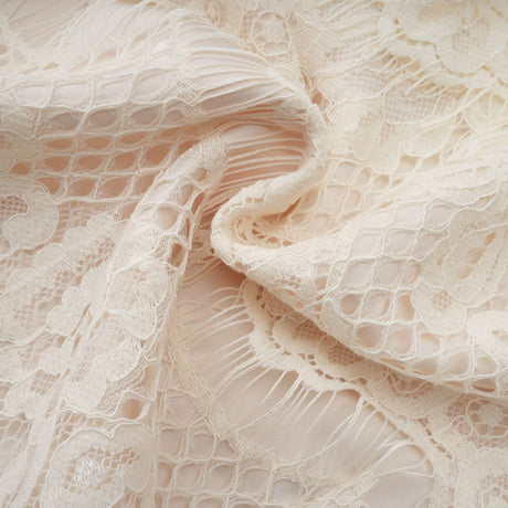 An offwhite blouse with floral lace detailing and a bow accent named Anaelle