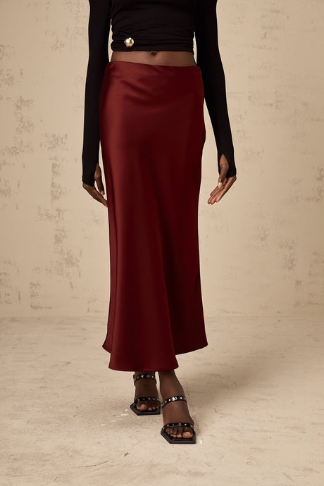 Bright red satin skirt with a flared silhouette hanging against a plain background