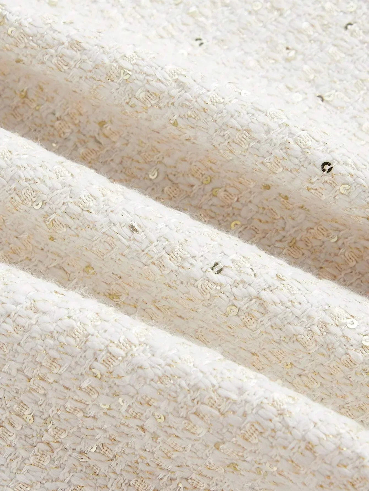 This elegant dress features a soft cream color with a textured, woven fabric that glimmers with subtle golden threads..
