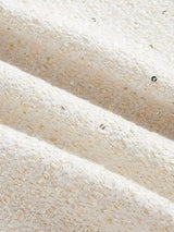 This elegant dress features a soft cream color with a textured, woven fabric that glimmers with subtle golden threads..