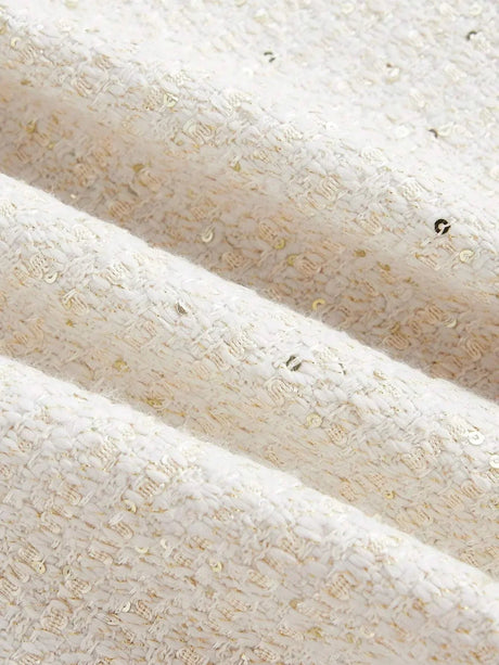 This elegant dress features a soft cream color with a textured, woven fabric that glimmers with subtle golden threads..