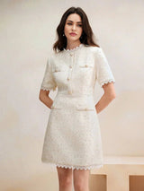 This elegant cream dress features a fitted silhouette with a chic high neckline, short sleeves, and delicate lace trim at.
