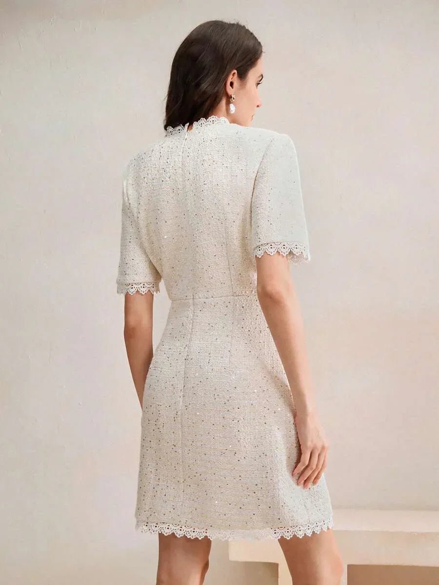 This elegant dress features a soft ivory hue with a textured fabric that adds dimension, while the delicate lace trim at the.