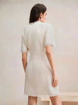 This elegant dress features a soft ivory hue with a textured fabric that adds dimension, while the delicate lace trim at the.