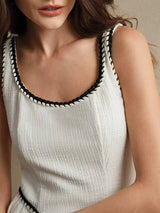 A stylish white dress featuring a textured fabric with a subtle ribbed pattern, elegantly framed by contrasting black trim.