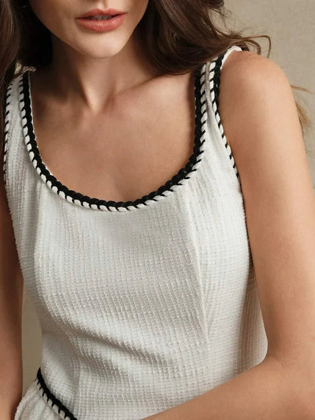 A stylish white dress featuring a textured fabric with a subtle ribbed pattern, elegantly framed by contrasting black trim.