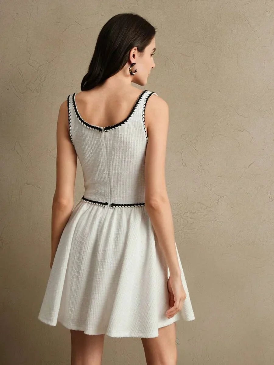 This delightful white dress features a flared skirt and a fitted bodice, accentuated by elegant black trim along the.
