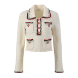 Elegant cream tweed jacket with red and black embroidery, decorative buttons, and a tailored fit