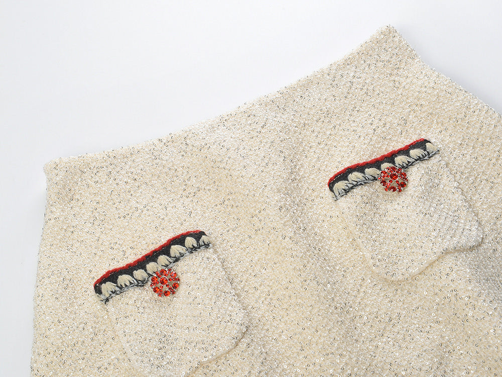 Elegant cream tweed jacket with red and black embroidery, decorative buttons, and a tailored fit