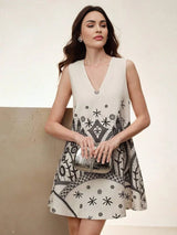 This sleeveless A-line dress features a chic V-neckline and a playful pattern of black abstract designs on a soft beige.