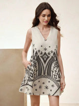 This stylish sleeveless dress features a chic V-neckline and a flattering flared fit, adorned with intricate black patterns.