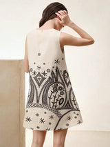 This stylish cream-colored dress features a trendy sleeveless design and a relaxed fit, adorned with intricate black.