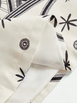 This elegant dress features a soft, cream fabric adorned with intricate black floral patterns, creating a charming contrast..