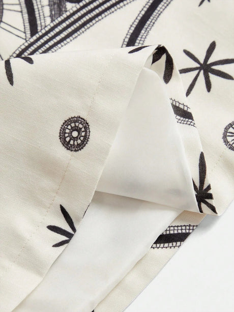 This elegant dress features a soft, cream fabric adorned with intricate black floral patterns, creating a charming contrast..