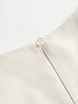 This elegant cream dress features a sleek, minimalist design with a delicate button detail at the neckline, crafted from a.