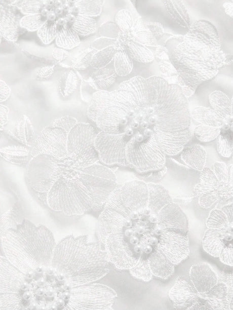 Elegant white dress featuring intricate floral embroidery and delicate pearl accents, creating a romantic and feminine.