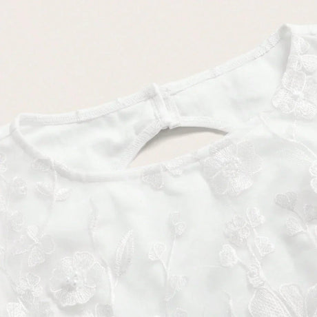 Delicate and chic, this white dress features intricate floral embroidery that adds a touch of elegance to its simple design..